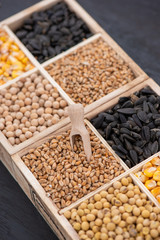 Obraz premium Small box with various grains and cereals on wooden table, top view, copy space