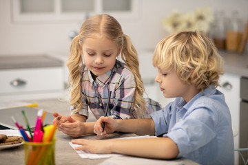 Two kids sitting at the table and drawing