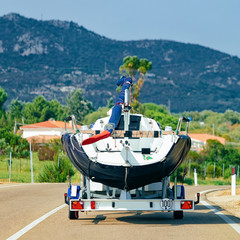 Car with yacht or motor boat on road in Sardinia