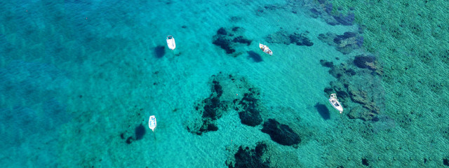 Fototapeta na wymiar Aerial drone ultra wide photo of traditional fishing boat docked in seaside village of Polonia, Milos island, Cyclades, Greece