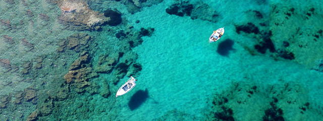 Fototapeta na wymiar Aerial drone ultra wide photo of traditional fishing boat docked in seaside village of Polonia, Milos island, Cyclades, Greece
