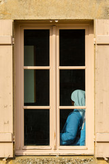 A Nun is Framed in a Window in a Churchyard in the Bourgogne Region of France