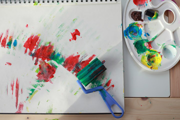 Child's hands paint with rollers and sponges and a palette