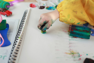 Close up child's hands paint with rollers and sponges and a palette