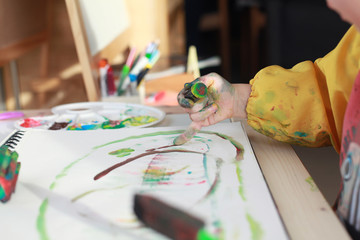 Close up child's hands paint with rollers and sponges and a palette