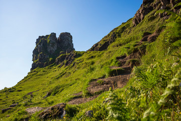 The otherworldly feel of the Fairy Glen, located at the end of a windy road near the Town of Uig, are small round-topped grassy hills with lochans, photographed on a cloudless day. 