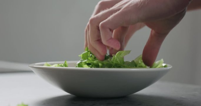 Slow motion add frisee salad leaves into white bowl