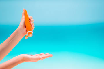 Beautiful young woman holding a suncream lying on tropical beach