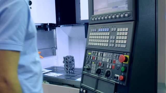 Person works behind the control panel of the production machine at the factory