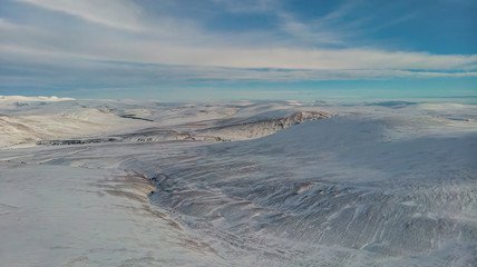 An aerial scenic view of a moutain range in the winter with snowy slope under a majestic blue sky...