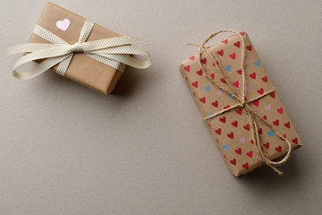 Gift boxes in crafting for Valentine's Day on a cardboard beige background with space for your creativity and space for text.