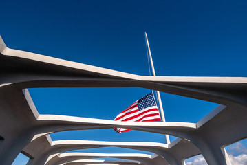 Oahu, Hawaii, USA. - January 10, 2012: Pearl Harbor. US Flag half pole over USS Arizona against blue sky. Seen through open ceiling of memorial.