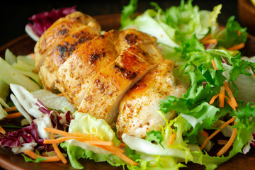 roasted chicken breast with mix salad of chicory, cabbage and lettuce on a plate close up.