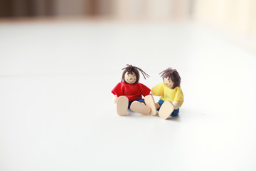 Group of four wooden flexible children puppets in colourful clothes standing on a white table 