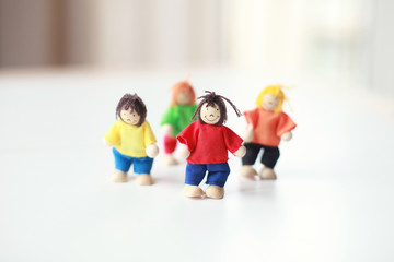 Group of four wooden flexible children puppets in colourful clothes standing on a white table 