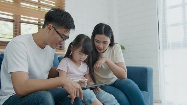 Happy asian family father mother and kid daughter sitting and using computer laptop technology. Little cute girl talking about her drawing to father and mother. Happy family relationship concept