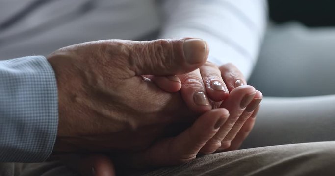 Close up elderly woman holding wrinkled hand of retired husband.