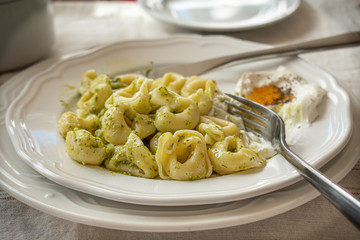 Cheese tortellini and pesto on white plate