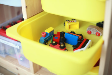 Yellow storage box in a classroom with a wooden toy trains