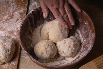 Balls of dough. Plywood cutting board, wooden flour sieve and wooden rolling pin - tools for making...