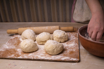 A woman kneads the dough. Plywood cutting board, wooden flour sieve and wooden rolling pin - tools for making dough.