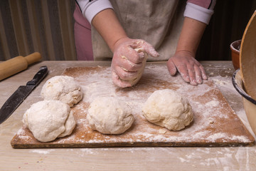 A woman kneads the dough. Plywood cutting board, wooden flour sieve and wooden rolling pin - tools for making dough.
