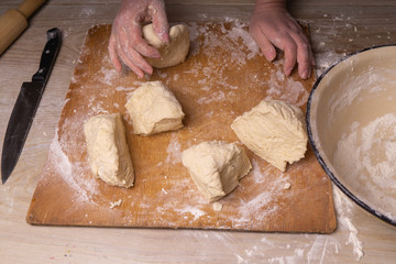 A woman kneads the dough. Plywood cutting board, wooden flour sieve and wooden rolling pin - tools for making dough.