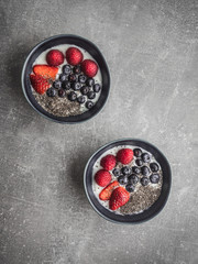 Two blue bowls with yoghurt and fruits. Overhead shot.