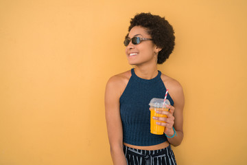 Young afro woman drinking fresh fruit juice.