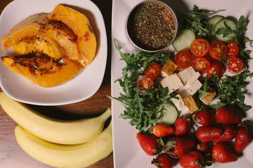 Vegetarian lunch bowl detox: sliced vegetables: cucumbers and tomatoes with herbs, spices and red strawberries and tofu, banana, pumpkin