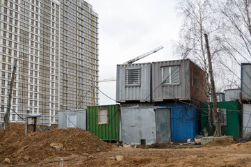 Fototapeta na wymiar Small temporary houses of builders from containers at an industrial construction site. Block-modular construction city with change houses for workers