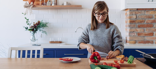 Young girl cutting paprika in the kitchen