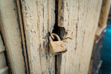 an old yellow lock weighs on the door. peeling paint