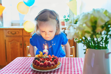 Happy toddler girl in blue dress celebrating her second birthday