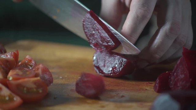 Chef slices beet on a cutting board in a restaurant. Prepare food on cuisine. Healthy nutrition in gourmet kitchen. Making meal. Prepare food to eat. Delicious dish. Cooking eating.