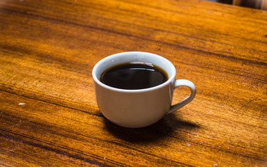 Withe cup with black coffee in a wood table