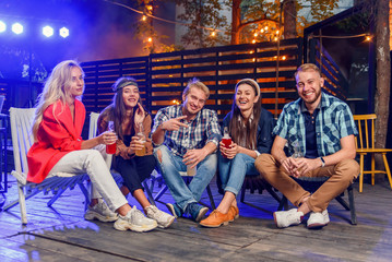 Young caucasian friends which enjoying time together on party at summer evening. Weekend, summer nights and lifestyle concept.