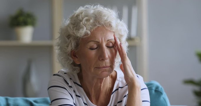 Tired mature older female pensioner having headache.