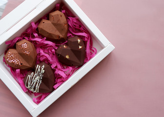 Handmade chocolates in a white gift box. Heart shaped sweets with milk chocolate with nuts.