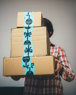 PARIS, FRANCE - DEC 2, 2018: Young Woman Holding Three Amazon Prime Parcel Cardboard Box Stack One Above Another Ready For Winter Holidays Gifts Shopping - On Time Delivery