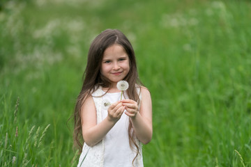 Portrait of a beautiful little girl with dandelions.