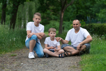 A father with his sons sits on the ground. Family portrait.