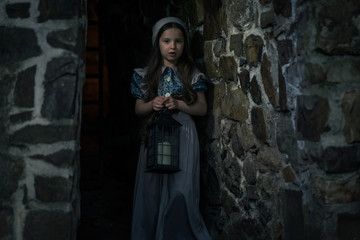 Frightened girl in the dungeons of an ancient castle. In her hand lantern.