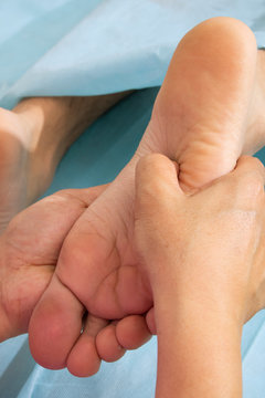 Young man suffering from podalgia at home, foot and toes massage