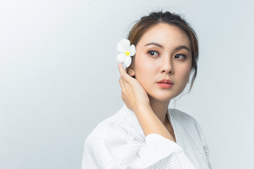 Beautiful young asian woman in spa uniform with flower. Beauty face care concept.