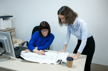 Office, a woman in a blue dress and a brunette girl working with drawings at a Desk