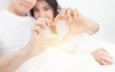 closeup hand and blur face on white, Asian lover show heart sign with hand, they feeling happy and smiling, happiness honeymoon