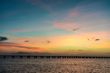 Fototapeta na wymiar The sun sets behind a bridge in Florida