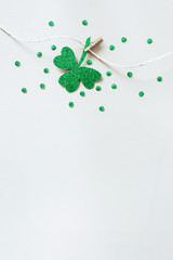 St. Patricks day concept. Glitter shamrocks garland. Shiny paper cut clover leaf on clothespin