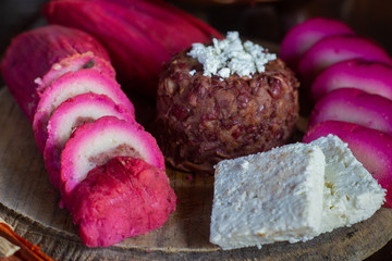 Tamal pisque traditional Nicaraguan food, along with fried beans and cheese on a rustic wooden board and with a natural coloring of the tree called "brasil"